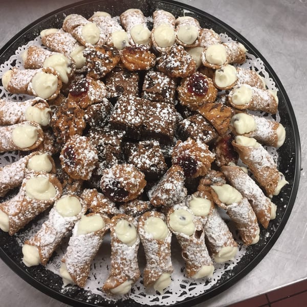 A platter of Dino's Pizza & Pasta cannolis and brownies dusted with powdered sugar.